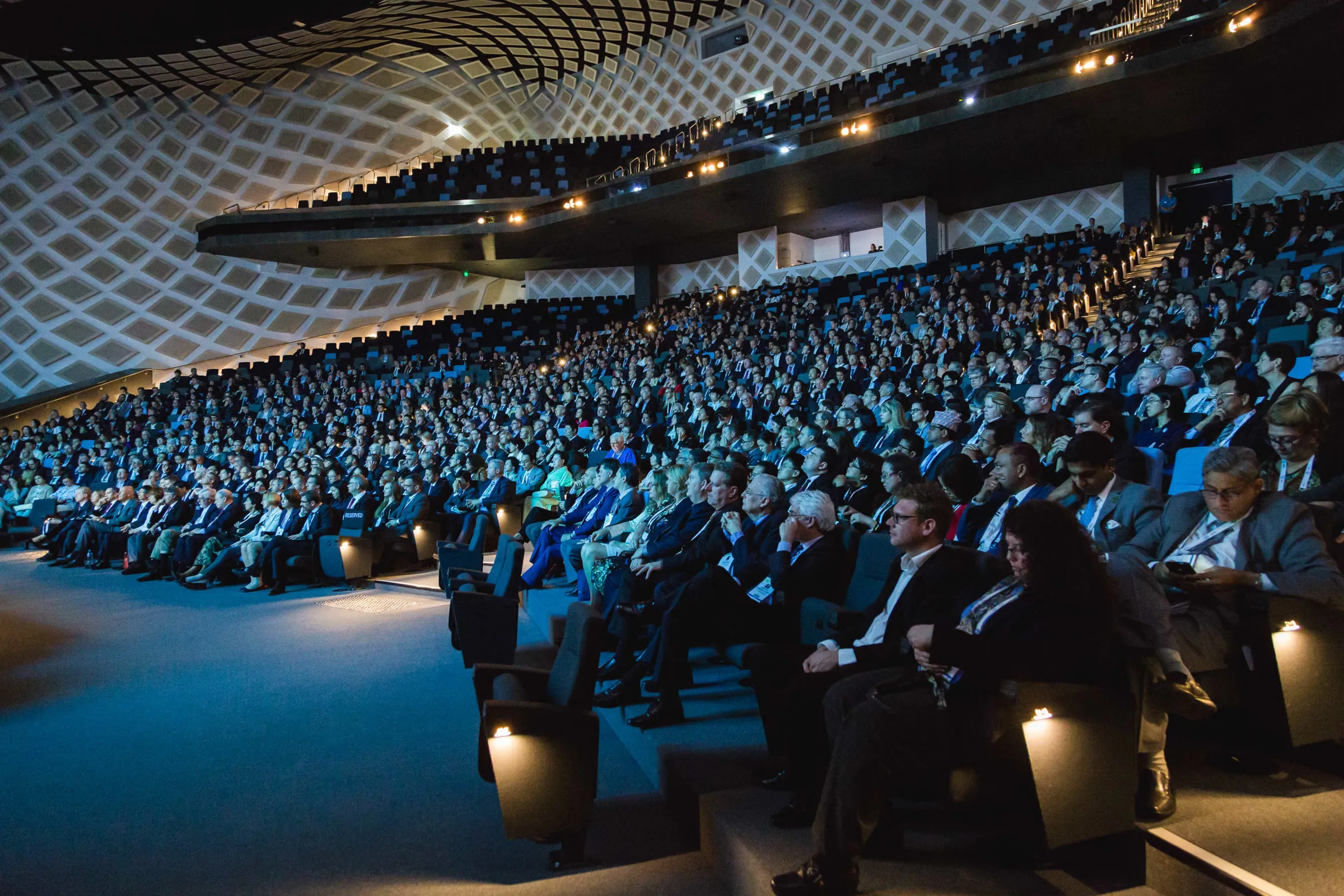 Wide view of a packed plenary session at ICC Sydney's Darling Harbour Theatre, with twin screens either side of the stage